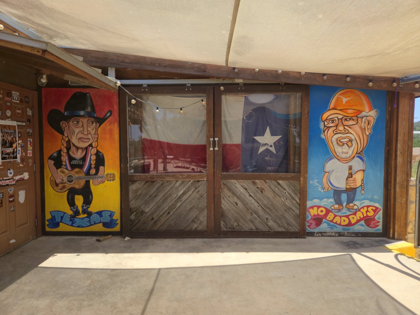 Murals of Willie Nelson and Poodie flanking the Texas-flag doors at the entrance